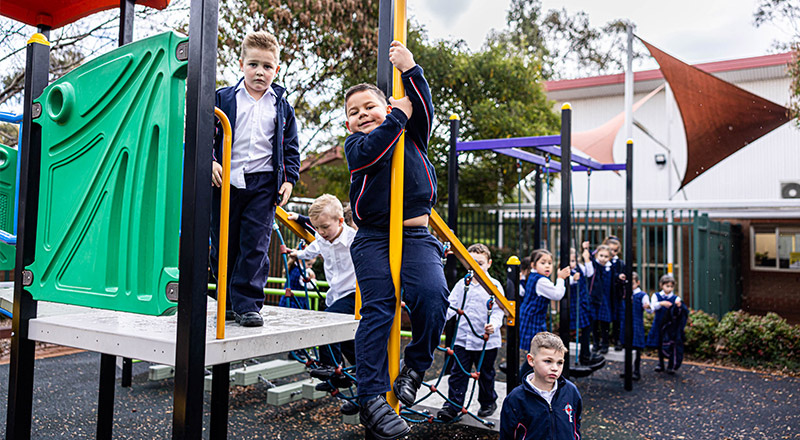 Student sliding down a pole in the playground at Bethany Catholic Primary School Glenmore Park
