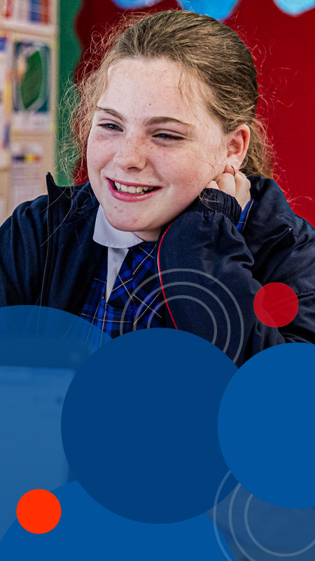 Student smiling in front of laptop at Bethany Catholic Primary School Glenmore Park